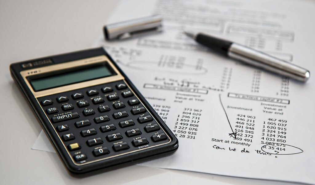 Calculator resting on a printed budget worksheet showing rows of numbers.