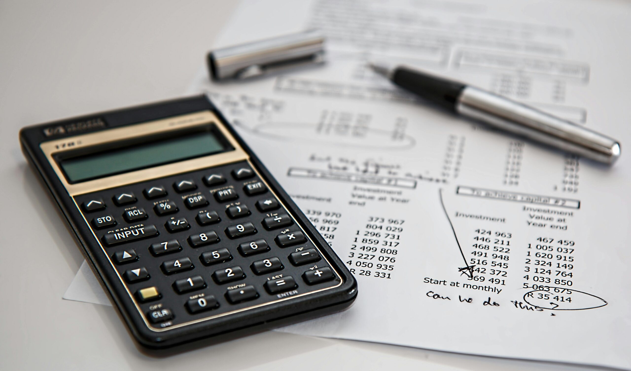 Calculator resting on a printed budget worksheet showing rows of numbers.